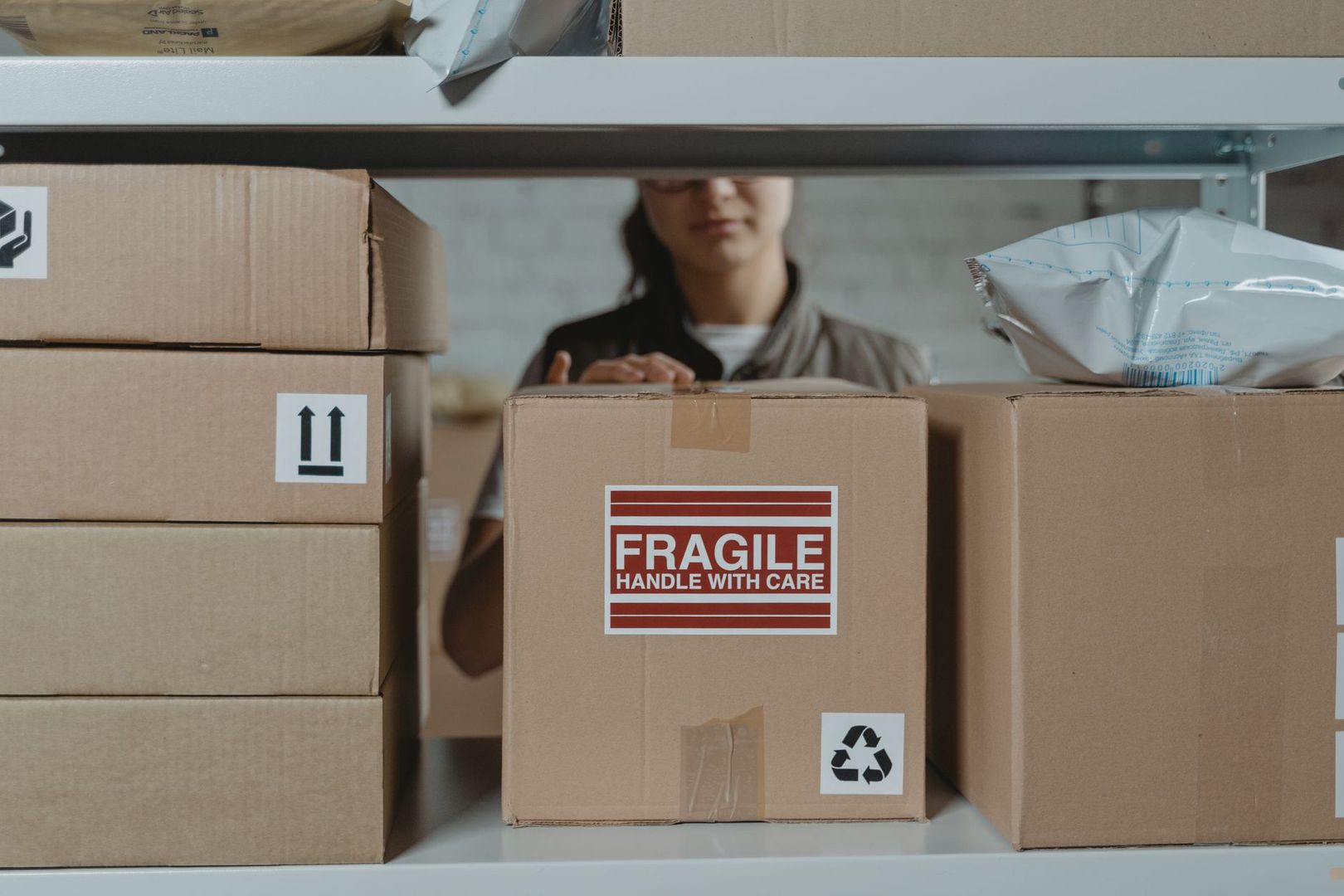 Kartonger på en lagerhylla med en tydlig Fragile-etikett för säker frakt med Sendify.