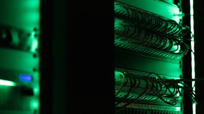 Serverrack med tätt anslutna nätverkskablar i grönt ljus